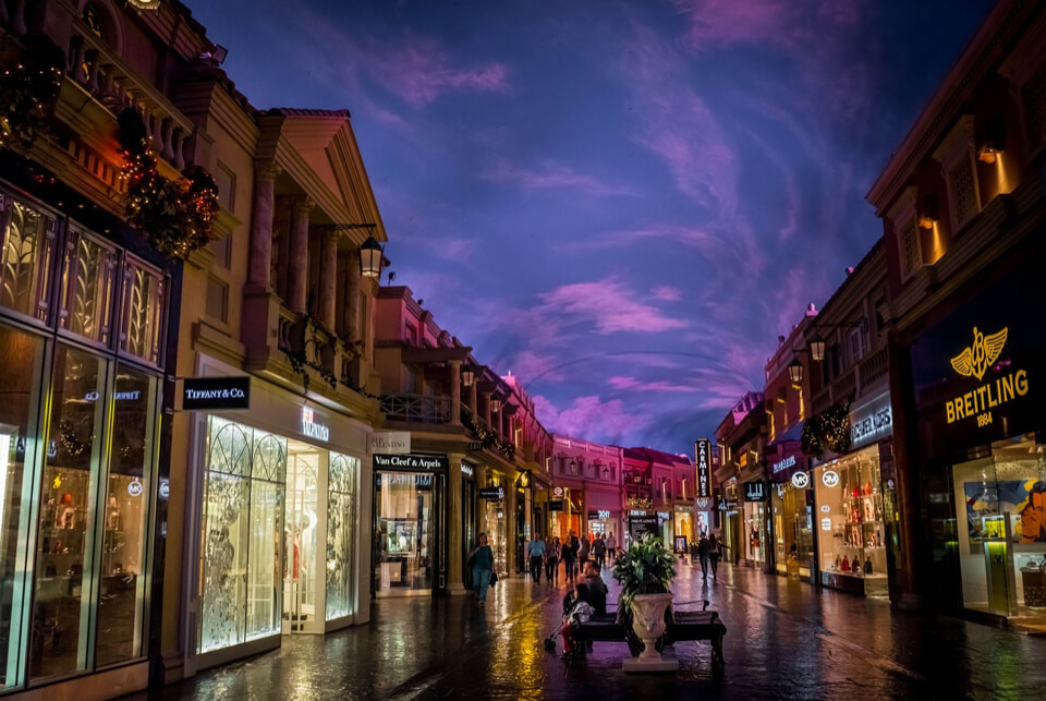 Via dello shopping di lusso illuminata a tarda notte.